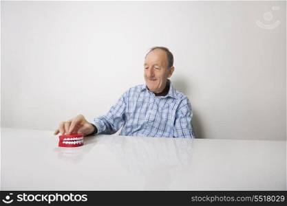 Happy senior man with dentures at table