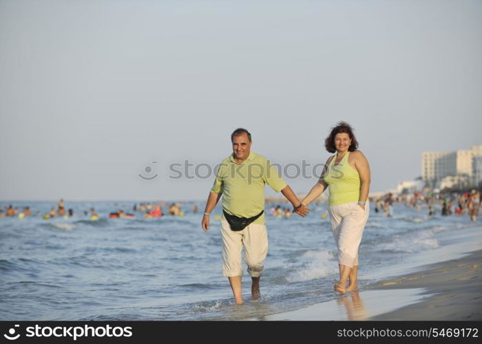 happy senior mature elderly people couple have romantic time on beach at sunset