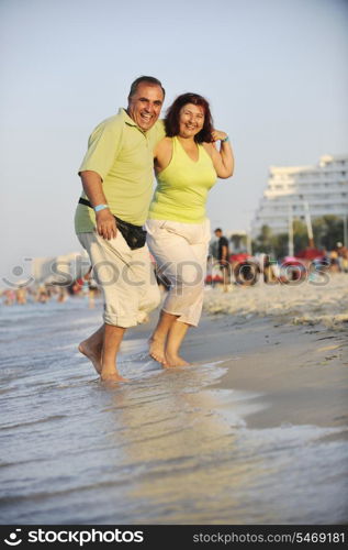 happy senior mature elderly people couple have romantic time on beach at sunset