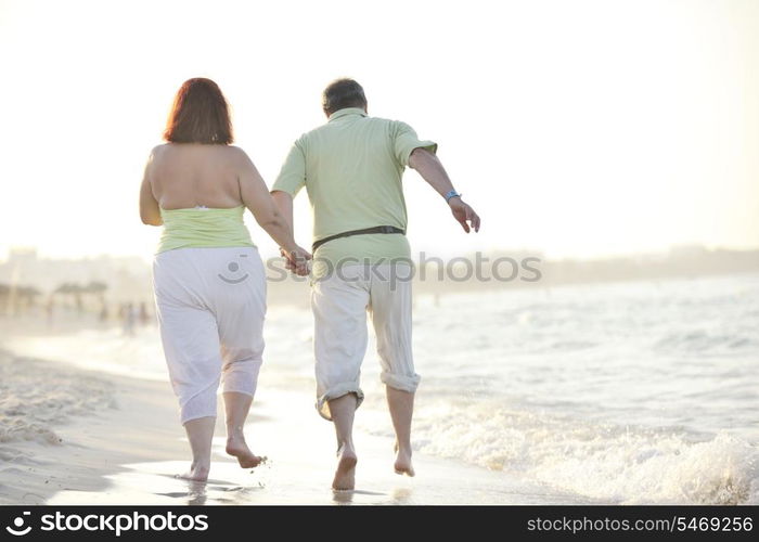 happy senior mature elderly people couple have romantic time on beach at sunset