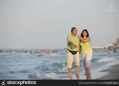 happy senior mature elderly people couple have romantic time on beach at sunset