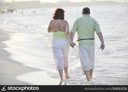 happy senior mature elderly people couple have romantic time on beach at sunset