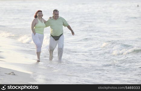 happy senior mature elderly people couple have romantic time on beach at sunset