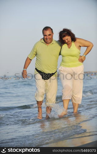 happy senior mature elderly people couple have romantic time on beach at sunset