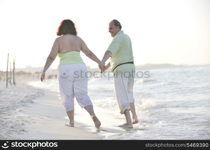 happy senior mature elderly people couple have romantic time on beach at sunset