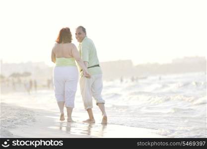 happy senior mature elderly people couple have romantic time on beach at sunset