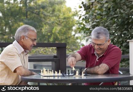 Happy senior men playing chess together