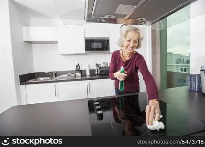 Happy senior woman cleaning kitchen counter