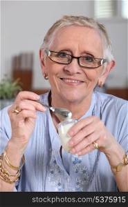 Happy senior woman eating yogurt