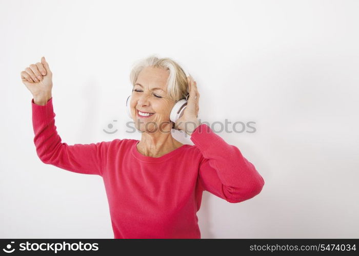 Happy senior woman listening music over white background