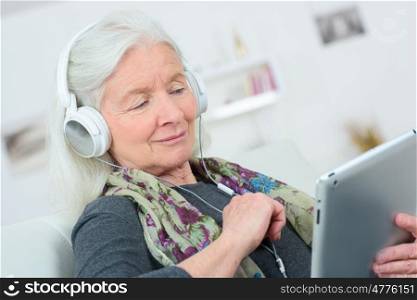 happy senior woman listening to music on digital tablet