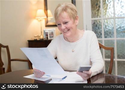 Happy Senior Woman Reviewing Domestic Finances At Home