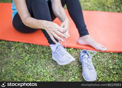 Happy senior woman tying shoe laces and sitting on the fittnes mat