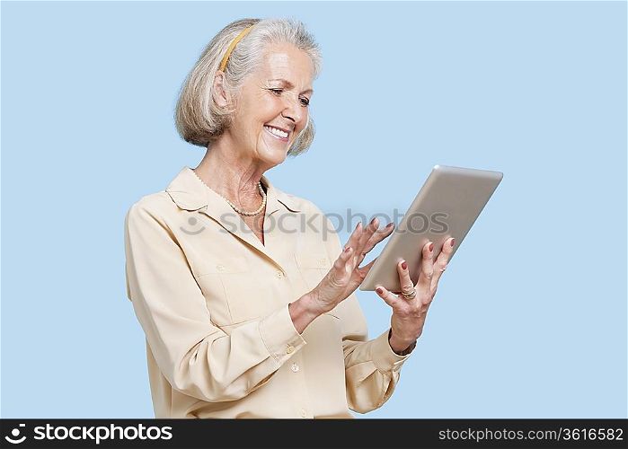 Happy senior woman using tablet PC against blue background