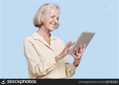 Happy senior woman using tablet PC against blue background