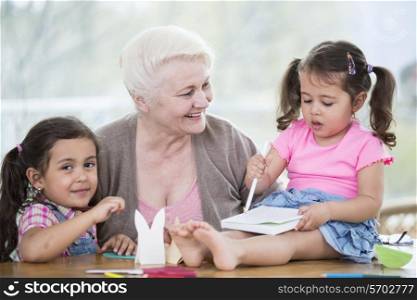 Happy senior woman with granddaughters making handicraft at home
