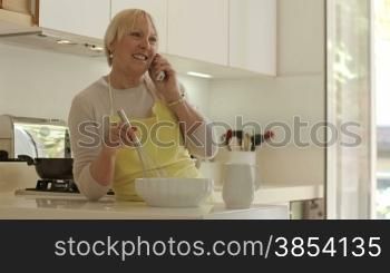 Happy senior women at home, cooking in kitchen and talking on the phone