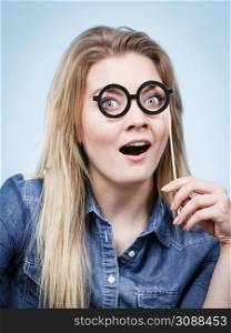 Happy shocked woman holding fake eyeglasses on stick having fun. Photo and carnival funny accessories concept.. Happy woman holding fake eyeglasses on stick