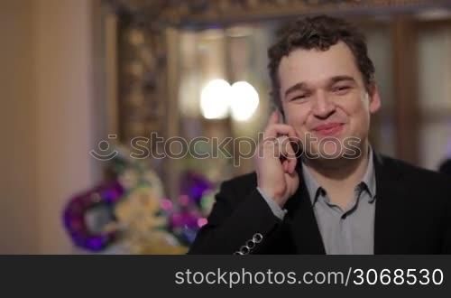 Happy smiling attractive business man chatting on a mobile phone while facing the camera with copyspace alongside