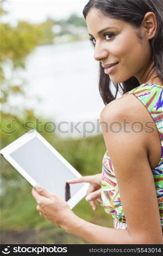 Happy, smiling, beautiful mixed race Latina Hispanic young woman or girl outside using tablet computer