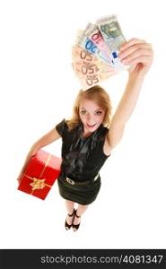 Happy smiling blonde girl young woman holding red christmas gift box and euro currency money banknotes. Holidays time for gifts.