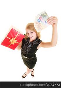 Happy smiling blonde girl young woman holding red christmas gift box and euro currency money banknotes. Holidays time for gifts.