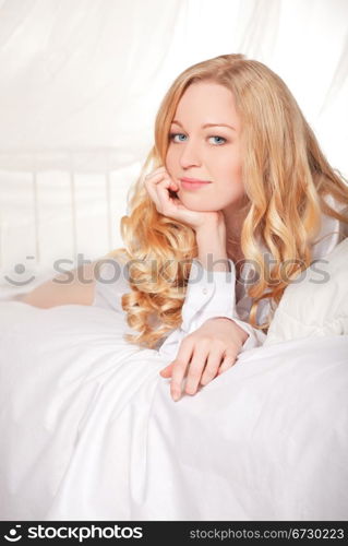 happy smiling blonde woman in bed at morning