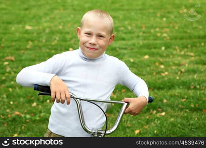 Happy smiling boy on a bicycle in the green park