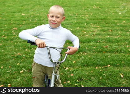 Happy smiling boy on a bicycle in the green park