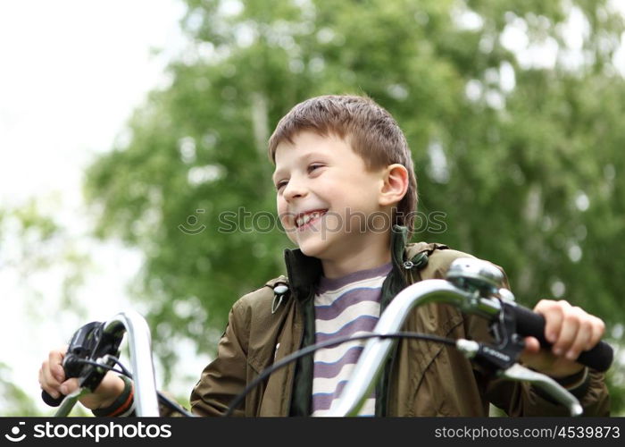 Happy smiling boy on a bicycle in the green park