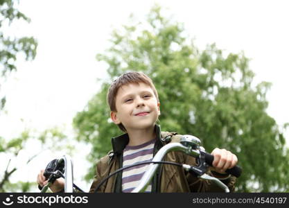 Happy smiling boy on a bicycle in the green park