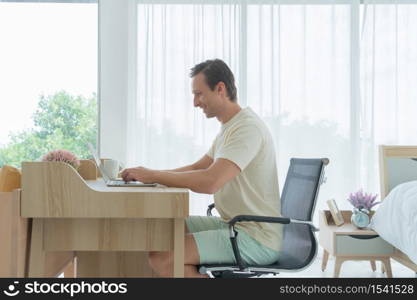 Happy smiling business blonde man. Freelance working from home online with laptop computer notebook in quarantine in corona virus pandemic concept.