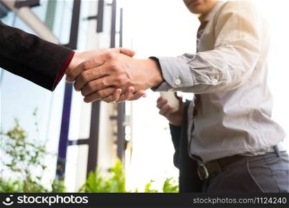 Happy smiling business man shaking hands after a deal finishing up a meeting, business outdoors concept.