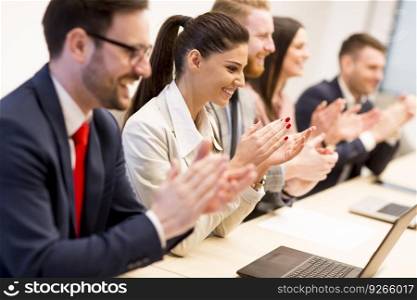 Happy smiling business team clapping hands during a meeting in office