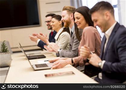 Happy smiling business team clapping hands during a meeting in office