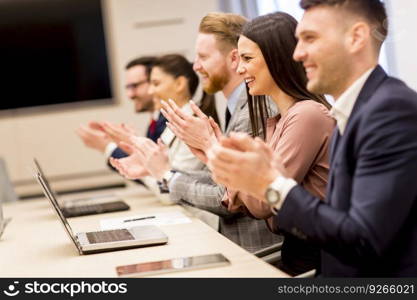 Happy smiling business team clapping hands during a meeting in office