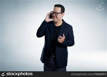 Happy smiling businessman wearing black suit and using modern smartphone with points a finger pose.