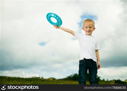 Happy smiling child in playground kid in action boy playing with blue frisbee disc. Active childhood