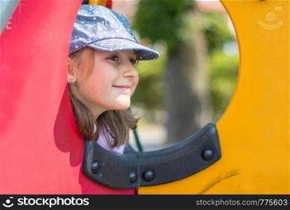 Happy smiling child in small house on playground
