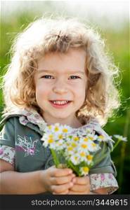 Happy smiling child with bunch of spring flowers in field