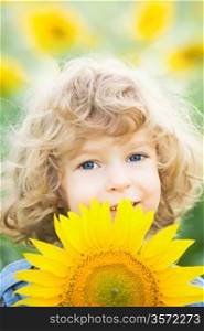 Happy smiling child with sunflower in spring field