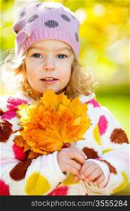 Happy smiling child with yellow maple leaves in autumn park