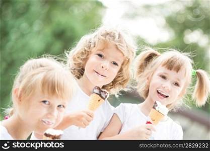 Happy smiling children eating ice-cream outdoors in spring park