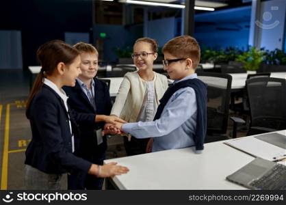 Happy smiling children stand in circle hold hands together. Business, teamwork, success celebration. Children standing in circle holding hands together