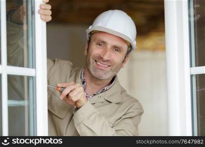 happy smiling constructor fixing a window