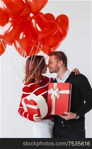 Happy smiling couple holding valentines day gifts and red balloons on white background. Valentines day couple with gifts