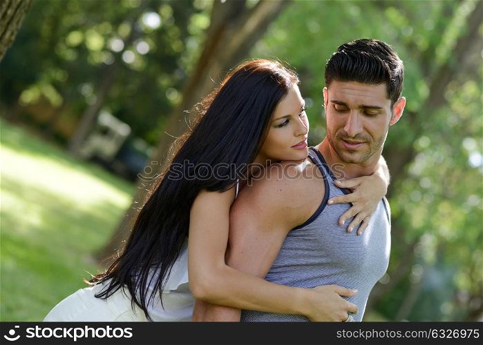 Happy smiling couple laying on green grass in a beautiful park
