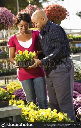 Happy smiling couple picking out flowers at outdoor plant market.