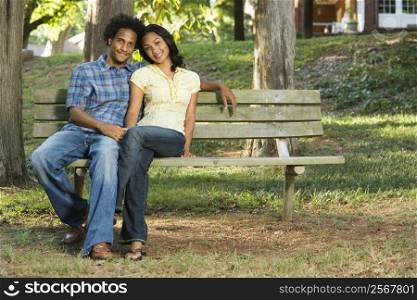 Happy smiling couple sitting on park bench together.