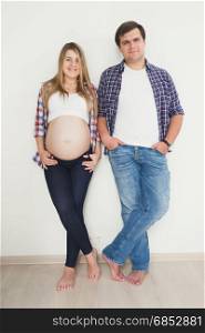 Happy smiling couple waiting for baby posing in jeans and shirts